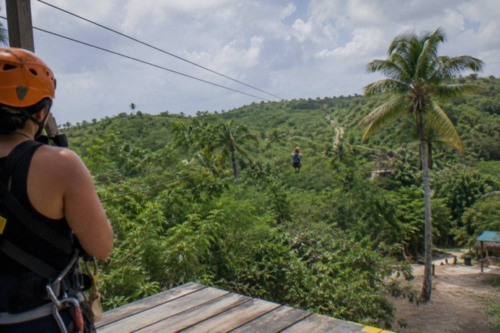 Zipline harness and helmet hanging on a wooden post beside a jungle platform