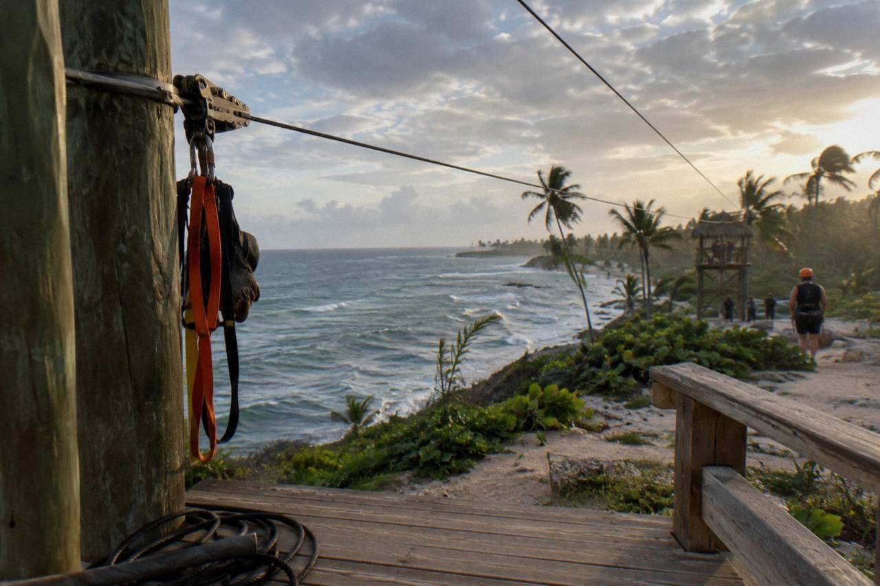 Zipline harness and helmet hanging on a wooden platform railing in a tropical forest