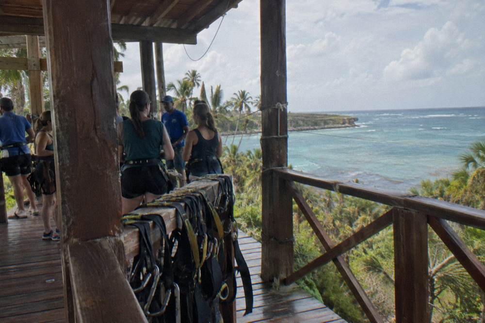 Group of travelers listening to a guide on a wooden zipline platform in the jungle