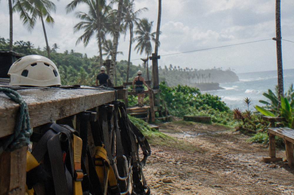 A pair of zipline harnesses and helmets hanging on a wooden rack