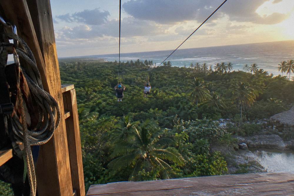 Two parallel zipline cables running side by side from a high wooden platform over treetops