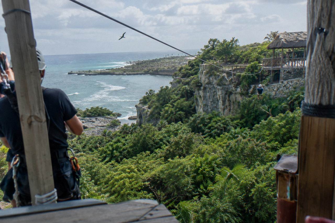 A zipline cable stretching between two wooden platforms above dense green jungle canopy