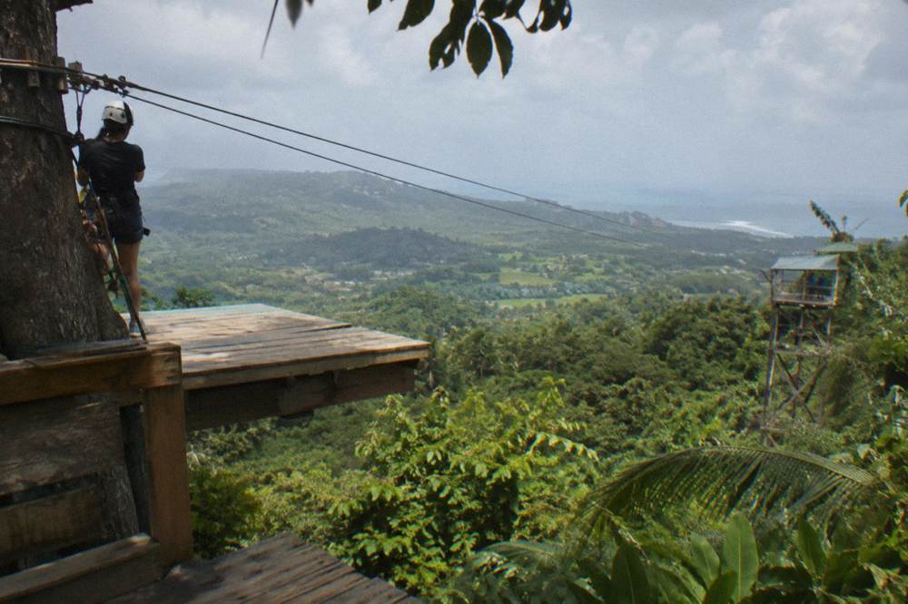 Wooden zipline platform with cables stretching over tropical treetops toward the next tower