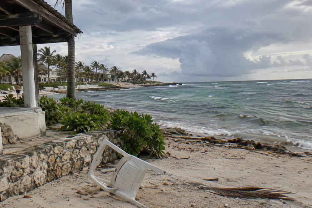 Dramatic tropical rainclouds gathering over calm sea and a line of beach umbrellas