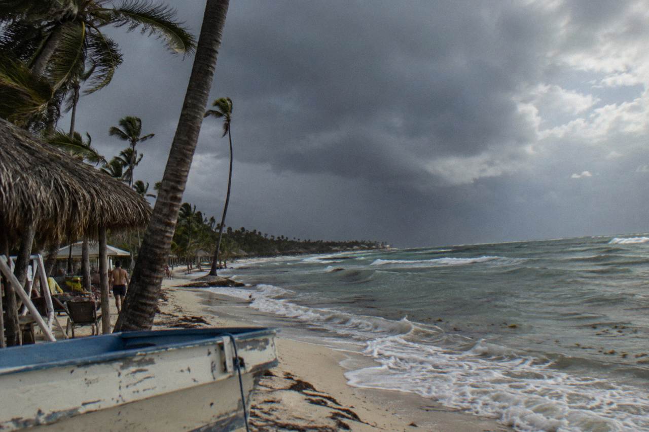 Dark rain clouds gathering over palm trees along a Caribbean beach