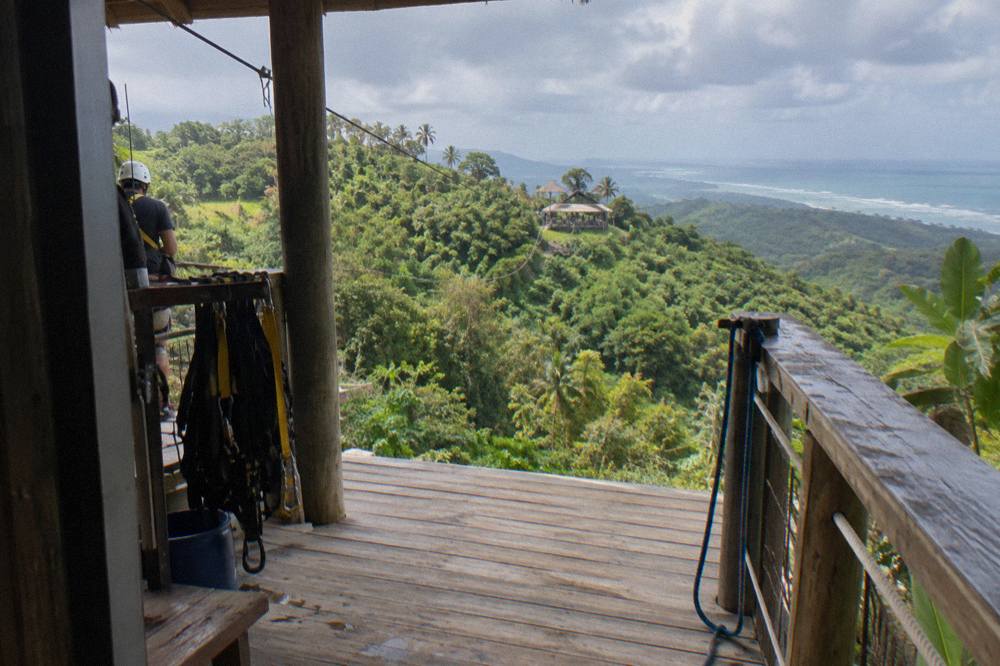 Wooden zipline platform built into a hillside overlooking forested mountains