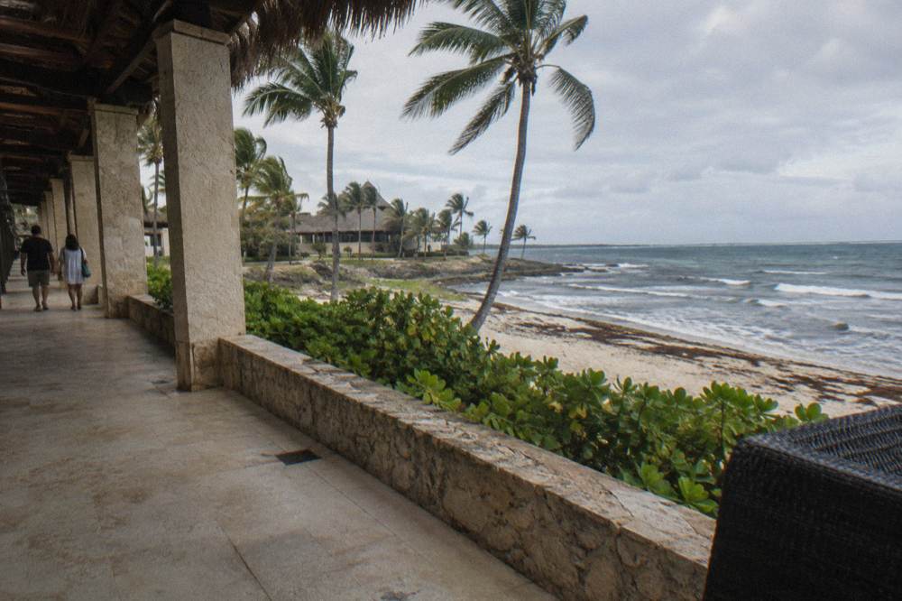 A family walking through a tropical resort corridor with small backpacks