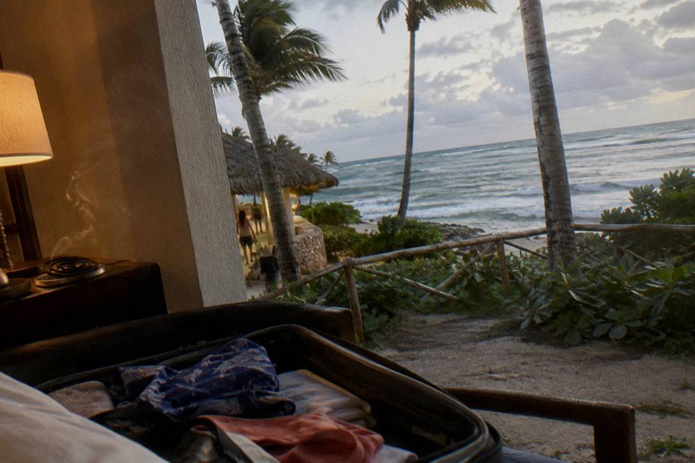 An open passport and boarding pass resting on a suitcase in hotel room light