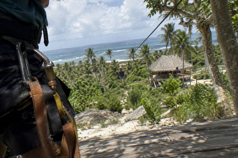 A zipline harness and helmet hanging on a wooden post under palm trees