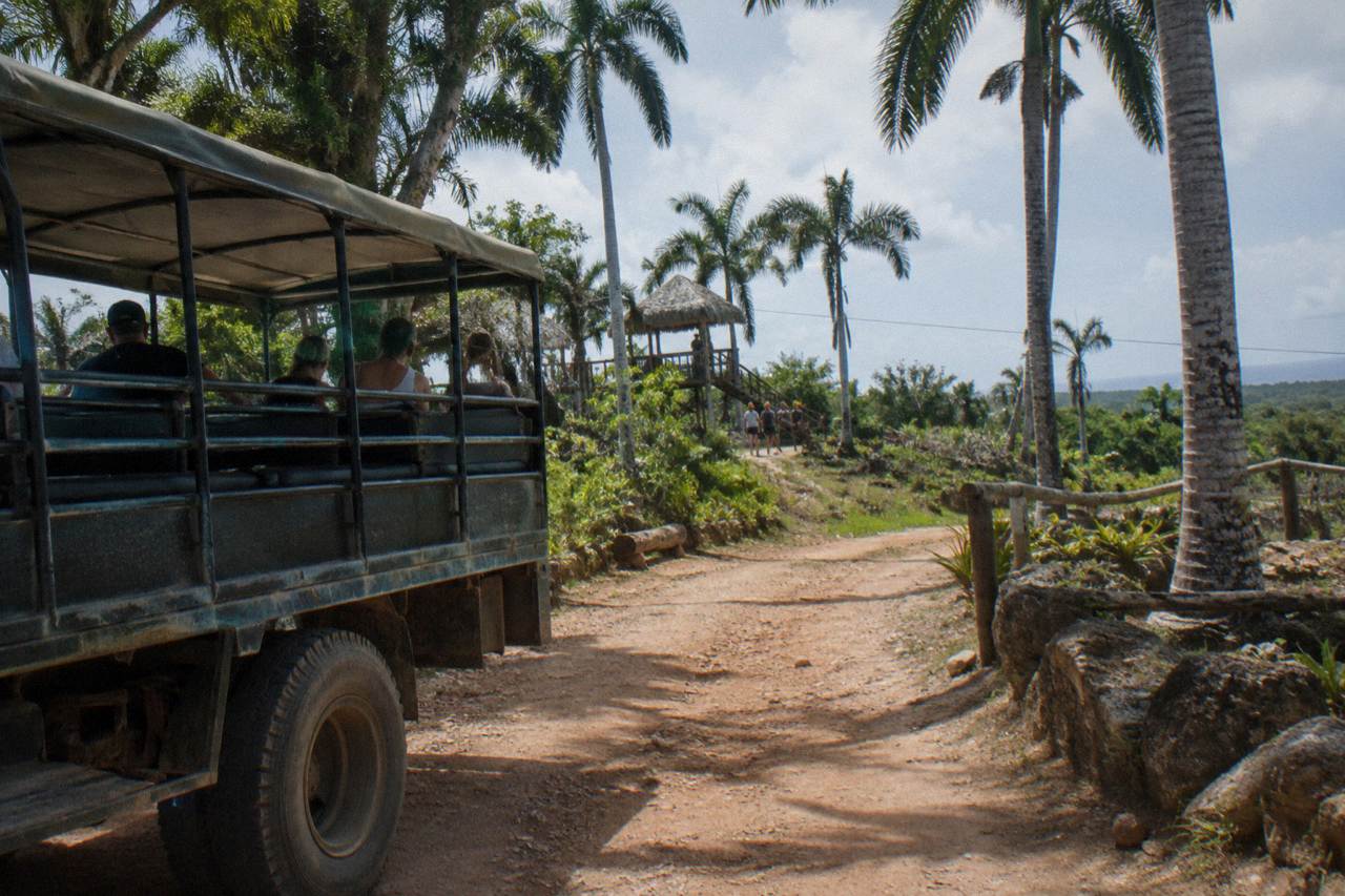 Open-air safari truck parked on a jungle road waiting for zipline tour guests