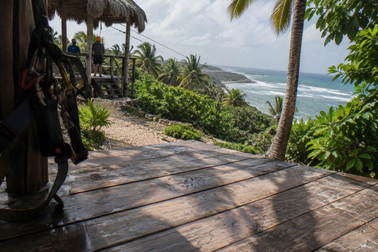 Zipline harness and helmet gear laid out on a wooden platform in a tropical forest
