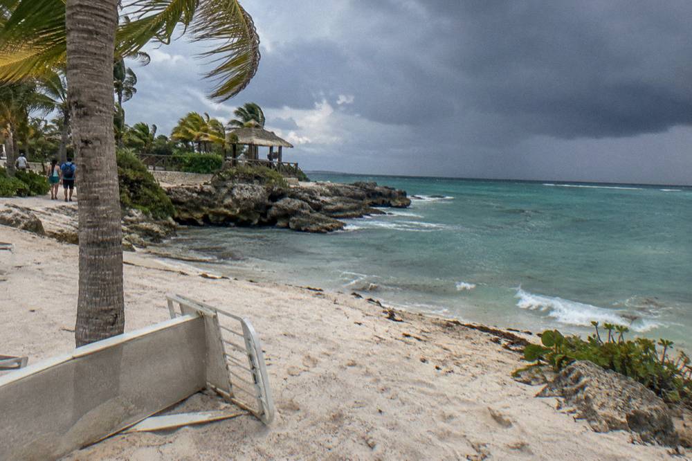 Tropical beach with dark storm clouds building on the horizon behind calm turquoise water