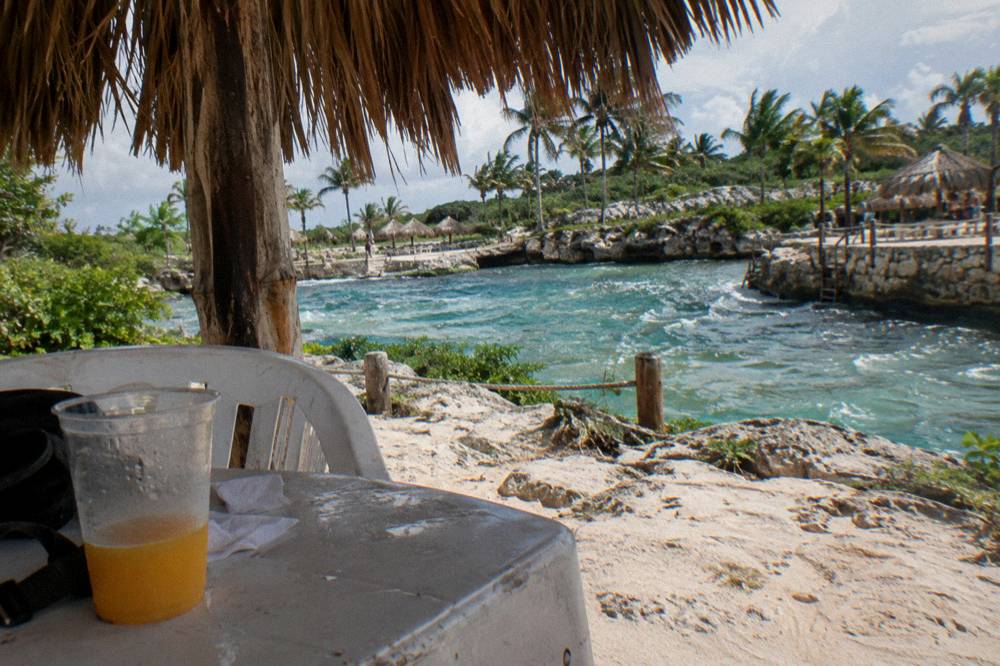 Shaded palapa seating area beside a beachside pool inside a tropical park