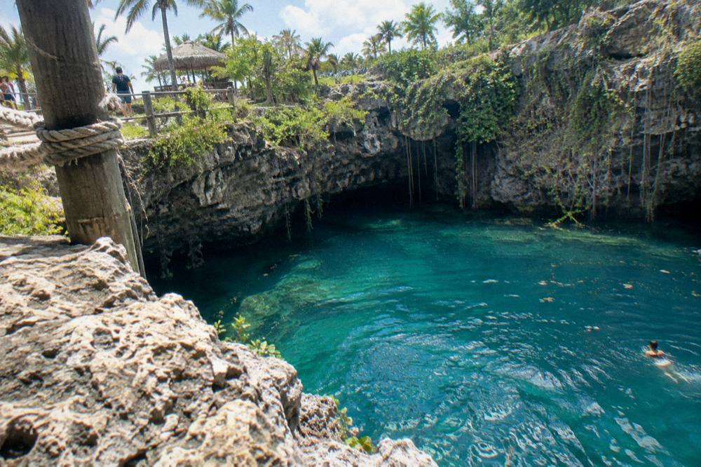 Turquoise water in a limestone cenote surrounded by rock walls and greenery