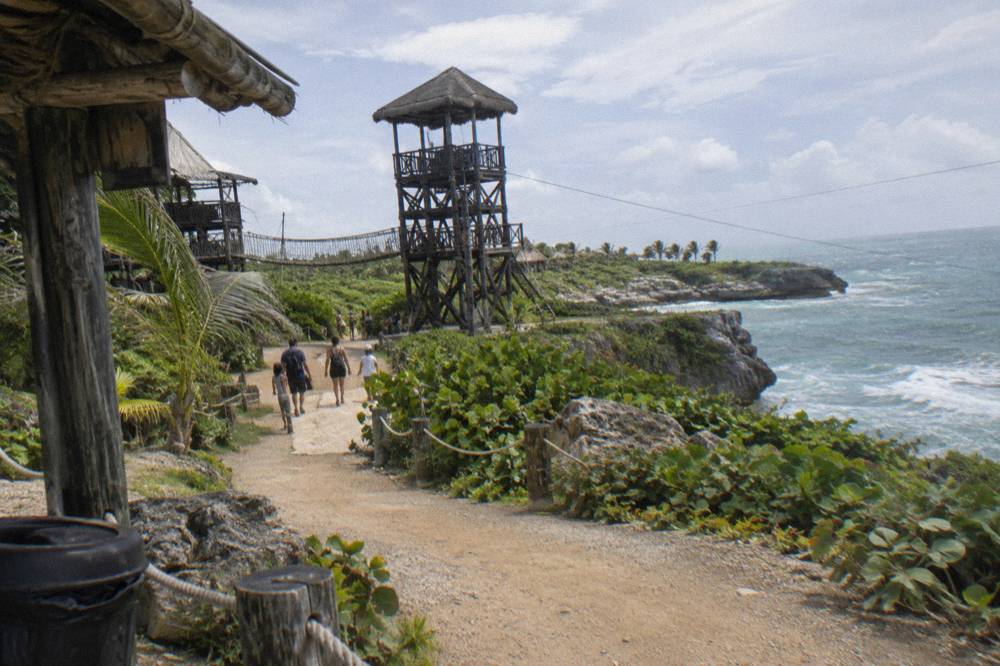 Families walking a shaded path between zipline platforms in a Punta Cana park