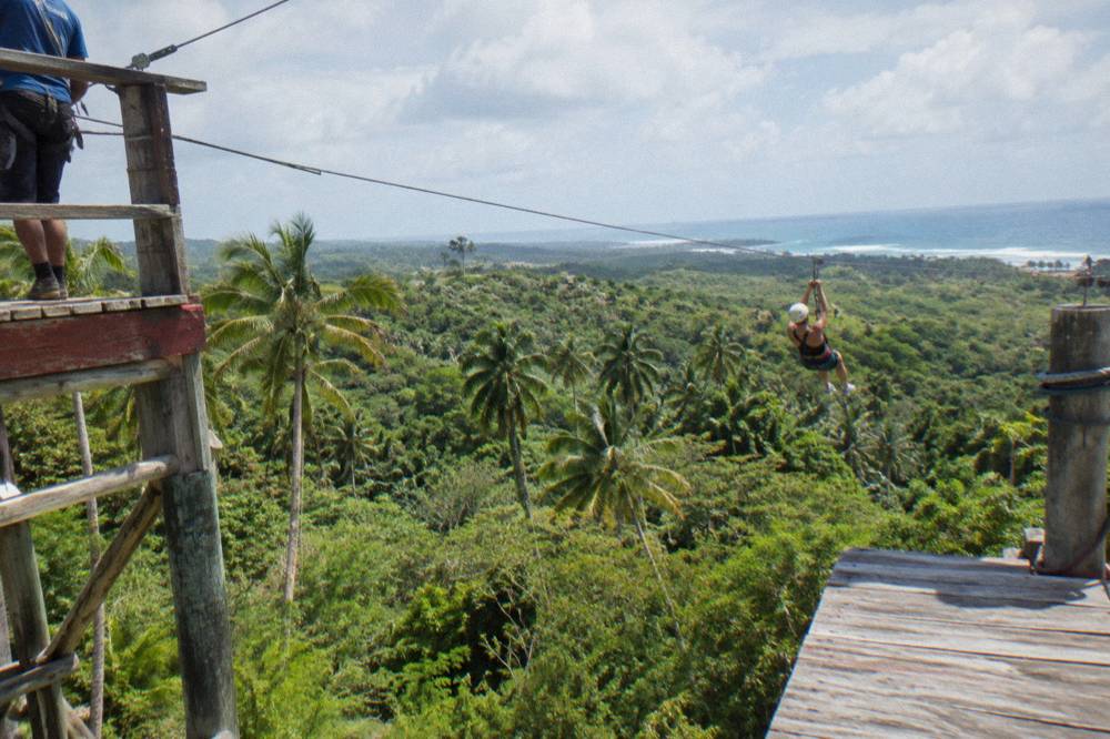 Zipline cable stretching between wooden platforms over dense green jungle canopy