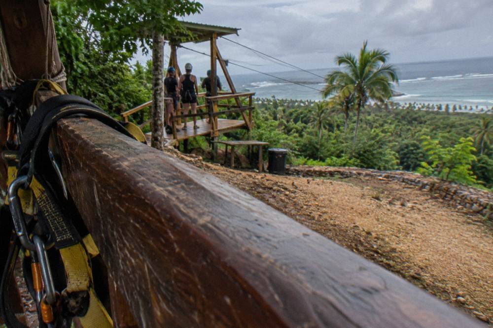 Harness and helmet hanging on a wooden rail at a jungle zipline base