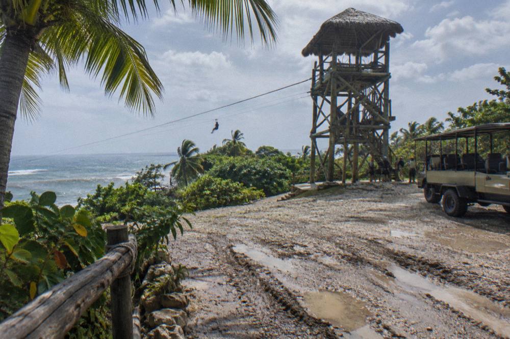 Tour vehicle and wooden zipline tower on a rural road in the Dominican countryside