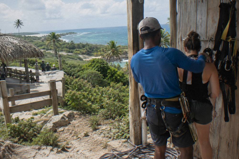 Guide tightening a safety harness on a participant at a jungle zipline base