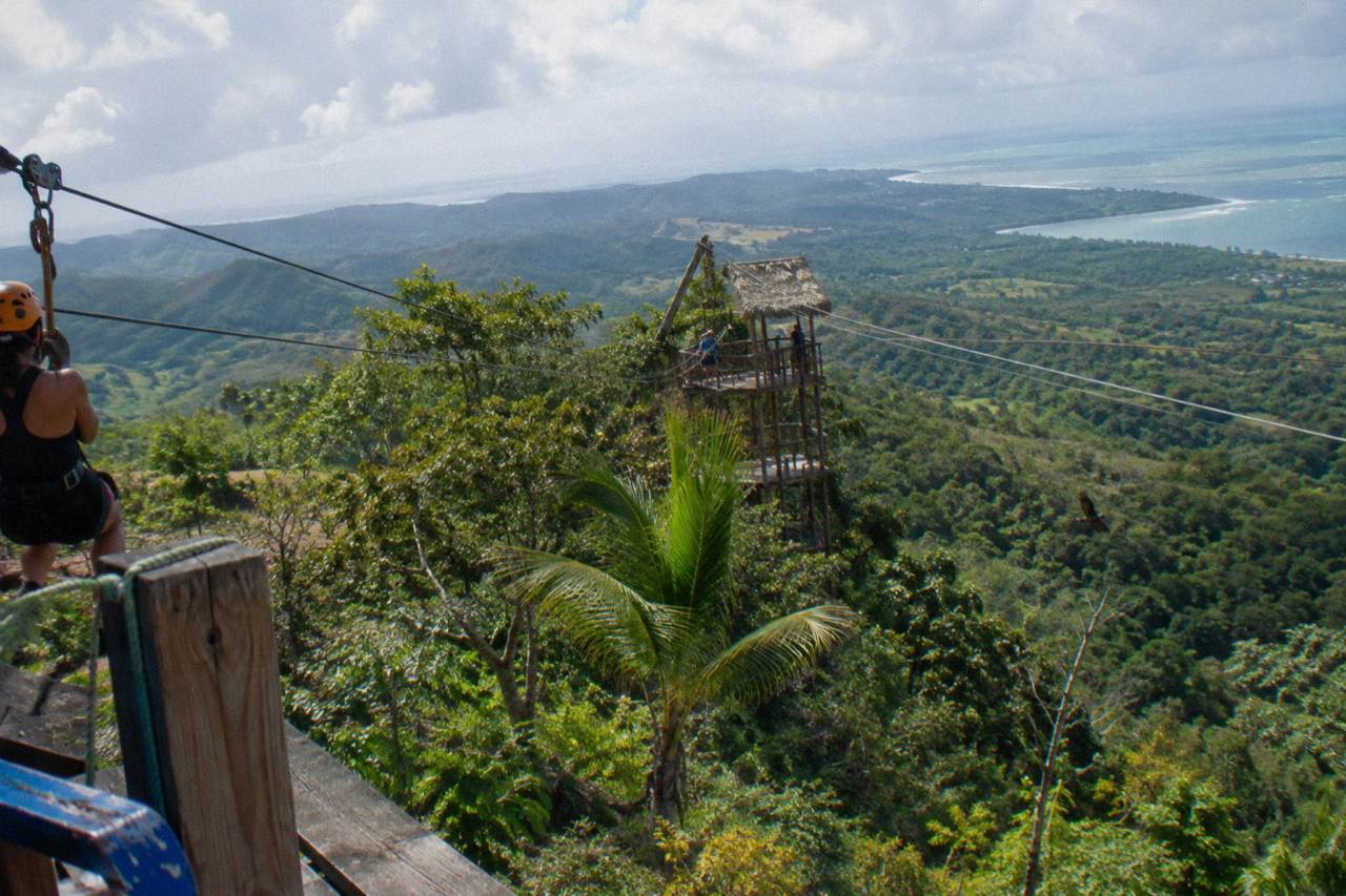 Zipline cables stretched between wooden platforms high in a green tropical mountain forest.