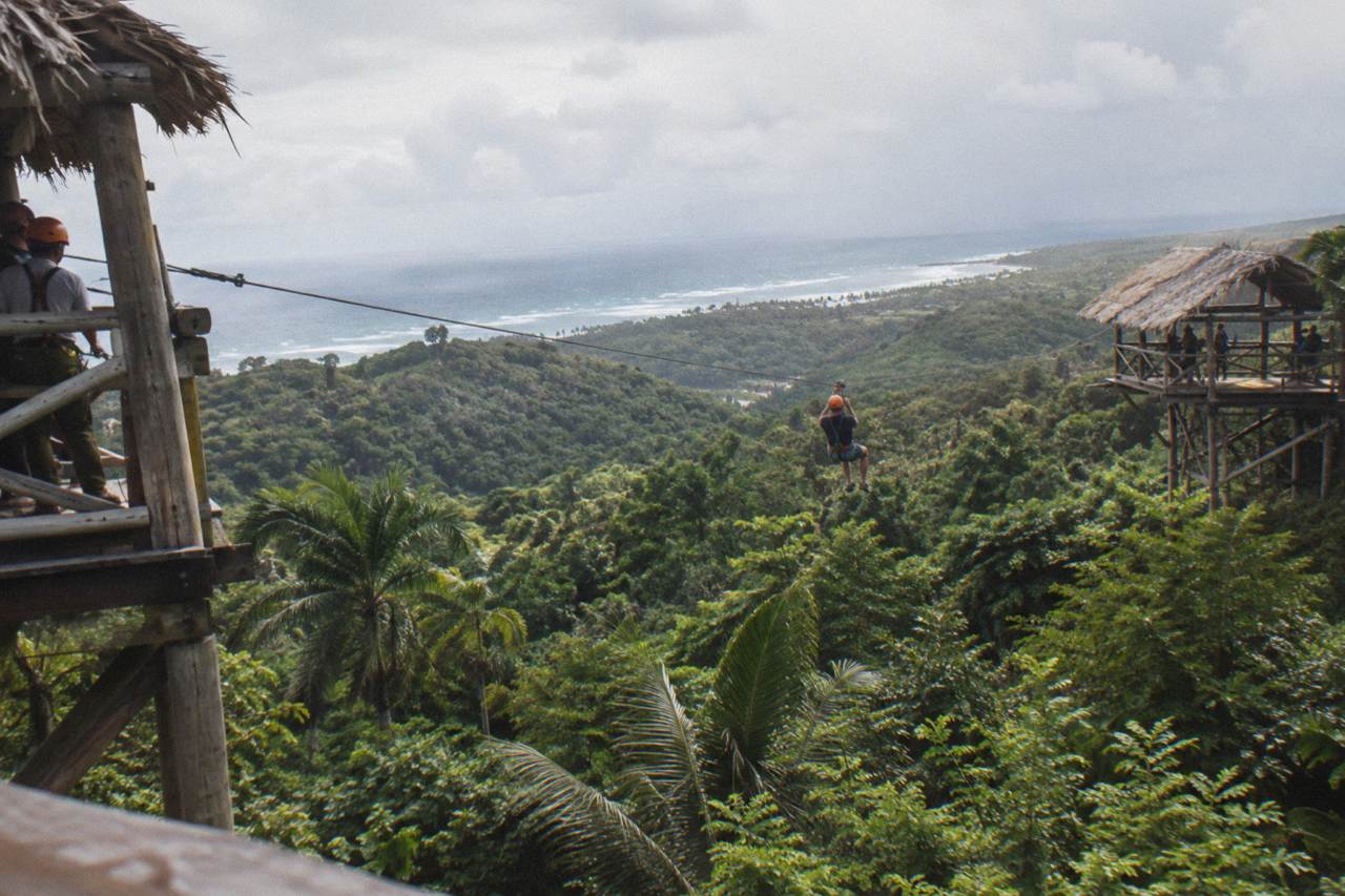 A zipline cable stretching between two wooden platforms above dense tropical forest