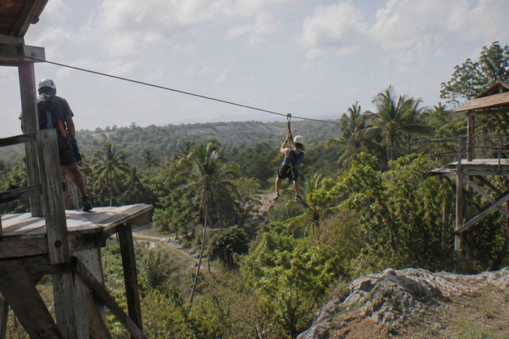 A zipline cable stretched between two wooden platforms above dense jungle canopy