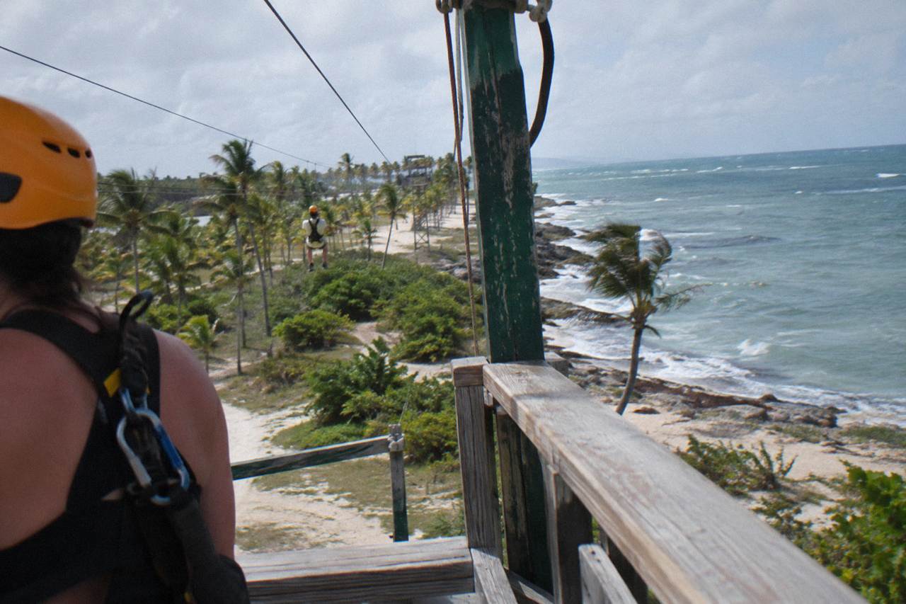 Zipline harness and helmet resting on a wooden platform in a tropical forest
