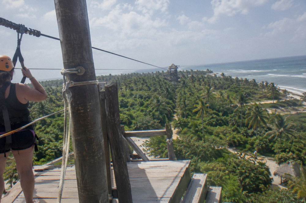 A wooden zipline platform above the jungle canopy with cables stretching to a distant tower