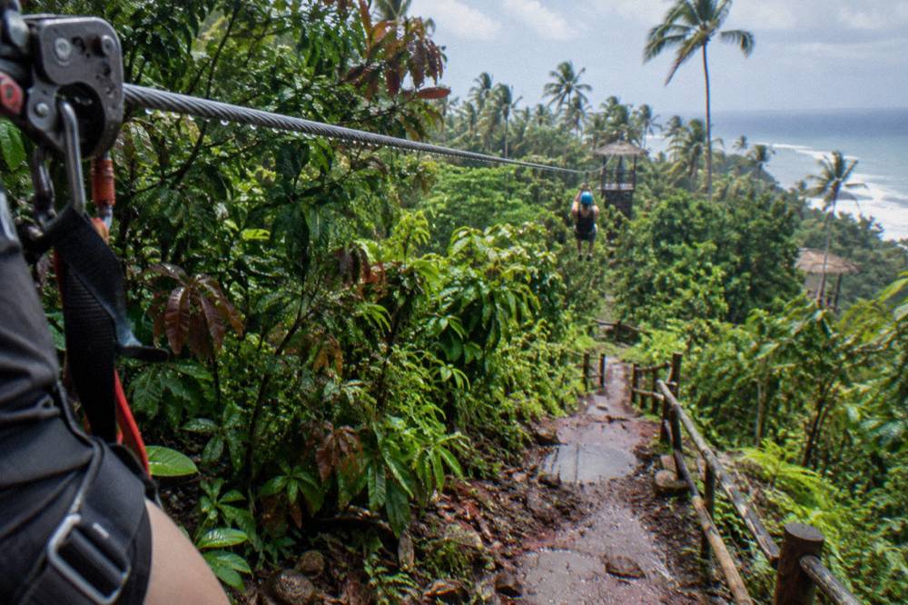 Water droplets on a zipline cable running through dense jungle vegetation
