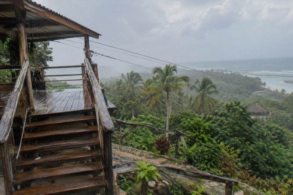 Empty zipline platform with rain falling on the wooden stairs and safety signage