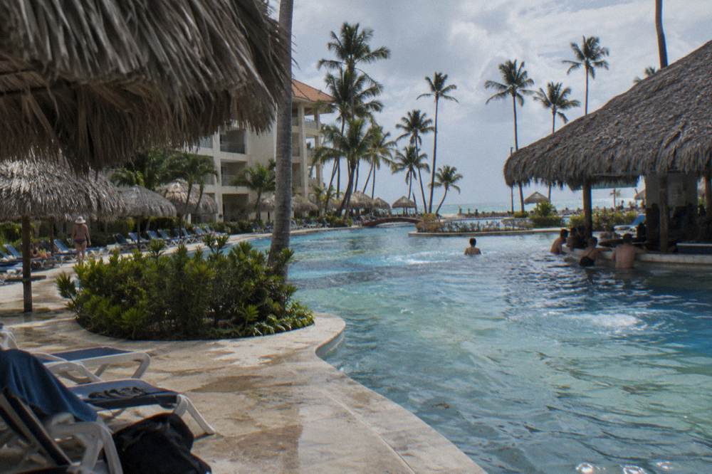Beach resort with winding pool, thatched umbrellas, loungers, and palms by the sea